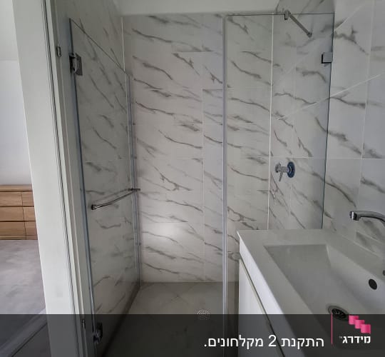 מקלחת עם אריחים לבנים וכיור לבן